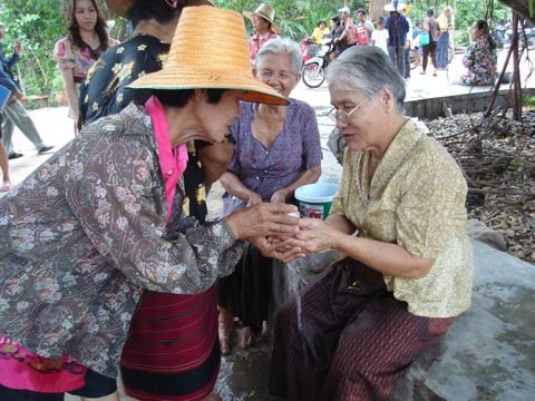 Songkran bij Wat Kungthapao: jongeren besprenkelen een oudere vrouw met water uit respect
